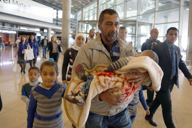 A Syrian family is escorted at the airport to catch a flight to the US, where they will have a refugee status as part of a programme to host 10,000 Syrians in America, on Wednesday  (Photo by Osama Aqarbeh)