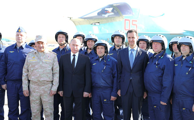 Russian President Vladimir Putin (2nd left) and President of Syria Bashar Assad (3rd right) pose for a photo with pilots at Hmeimim airbase in Latakia, Syria, on Monday (Anadolu Agency photo)