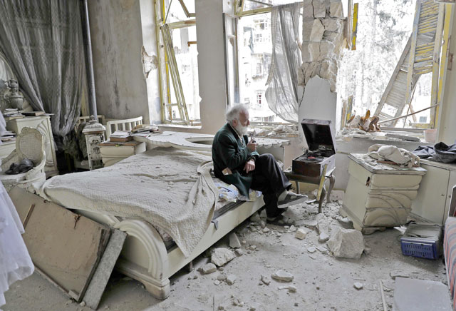 Mohammad Mohiedine Anis, 70, smokes his pipe as he sits in his destroyed bedroom listening to music on his vinyl player in Aleppo’s formerly rebel-held Al Shaar neighbourhood (AFP photo)