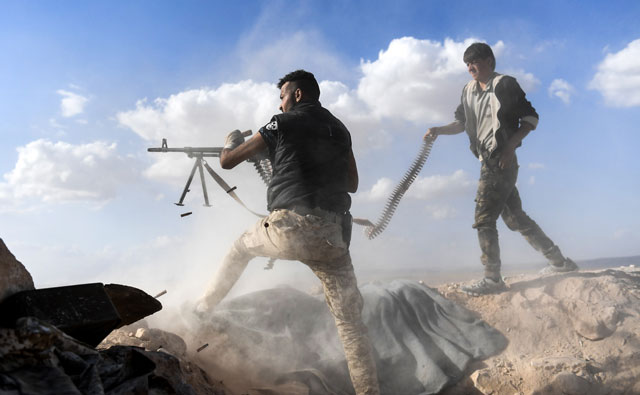 A member of the Syrian pro-regime forces fires from a machinegun as a comrade holds his feeding ammunition belt, during the advance towards rebel-held positions west of Aleppo, near Abu Al Zuhur military airport in the Idlib province countryside, on Saturday (AFP photo by George Ourfalian)