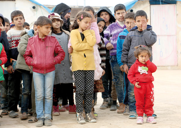 Syrian students pose for a photo while covering their left eyes with their hands in support of the Syrian baby Kerim, who lost his left eye, and his mother, after a reported government attack on a marketplace at Hammuriye district, at the Tecemmu Sermeda refugee camp in Qah Village of Idlib, Syria, on Wednesday (Anadolu Agency photo)