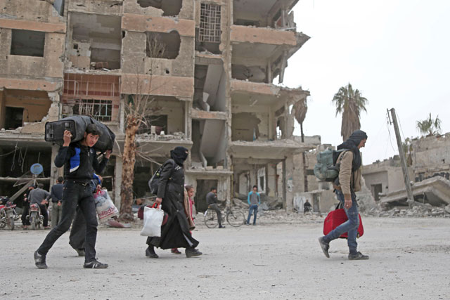 Syrian people walk down a destroyed street as they prepare to evacuate one of the few remaining rebel-held pockets in Arbin, in Eastern Ghouta, on the outskirts of the Syrian capital Damascus, on Saturday (AFP photo)