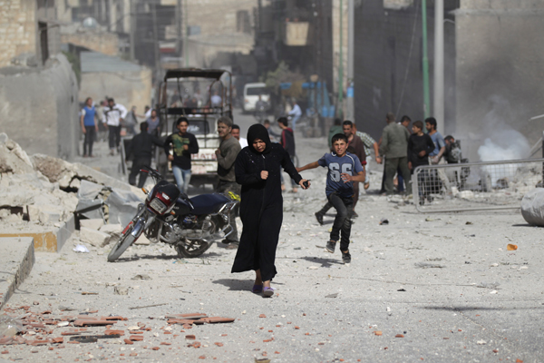 A woman runs holding a walkie-talkie towards a damaged site after an air strike on the rebel-controlled area of Maaret Al Numan town in Idlib province, Syria, on Tuesday (Reuters photo)