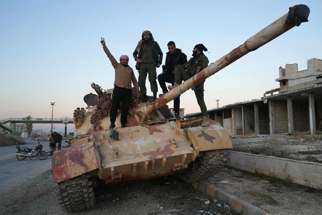 Extremist-led rebels pose for a picture on a tank on the road leading to Maaret Al Numan in Syria's northwestern Idlib province on November 30, 2024 (AFP photo)