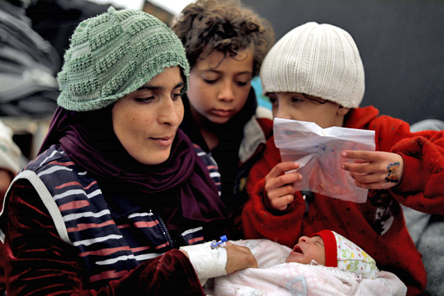 Kamela Fadel, a displaced Syrian woman from the locality of Al Shaafa, holds her newborn Faraj in her arms at the Internallly Displaced People camp of Al Hol in Al Hasakeh governorate in northeastern Syria, on Saturday (AFP photo)