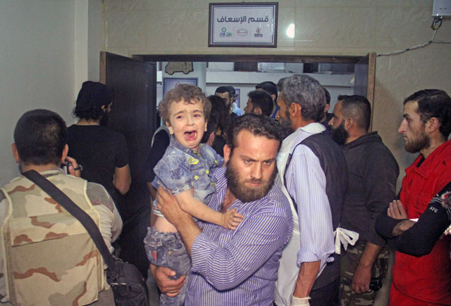 A man carries a crying child at a hospital following Russian air strikes that targeted many areas in Syria’s northwestern city of Idlib early Tuesday, according to the Syrian Observatory for Human Rights (AFP photo by Omar Haj Kadour)