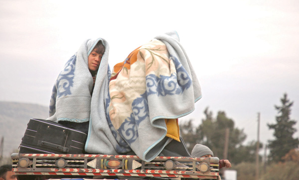 Children clad in blankets, sit in the back of a truck on a road near the town of Al Ghazawiya as they flee pro-Syrian forces attacks on the western countryside of Aleppo, to seek refuge in safer areas near the Turkish border on Tuesday (AFP photo)