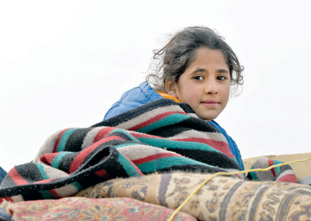 A displaced Syrian child rides in the back of a truck passing by Dayr Ballut on the way to Afrin and Azaz near the Turkish border in the rebel-held part of Syria's Aleppo province on Friday, fleeing from government forces advancing in the Idlib and Aleppo regions (AFP photo)