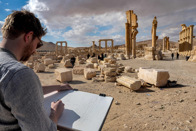 A visitor sketches while seated before the Great Colonnade (Decumanus Maximus) at the ancient ruins of Palmyra in central Syria on February 7, 2025 (AFP Photo)