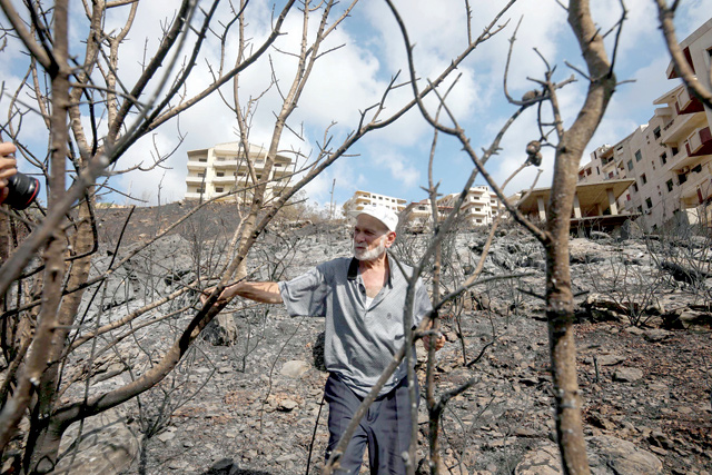 A Syrian man inspects a scorched area in the aftermath of a forest fire which ravaged swathes of land in the countryside of the western city of Tartus on Sunday (AFP photo)