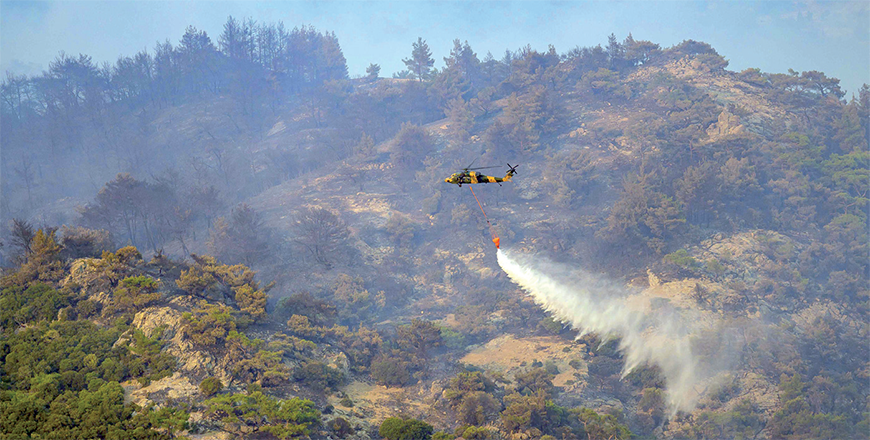 This photograph shows a helicopter dousing water to fight a forest fire in Turkey's western province of Izmir on Saturday (AFP photo)