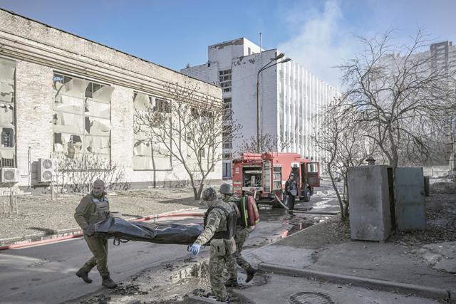 Military emergency service members remove the body of a dead Ukrainian serviceman in the area of a research institute, part of Ukraine's National Academy of Science, after a strike, in north-western Kyiv, on Tuesday (AFP photo)