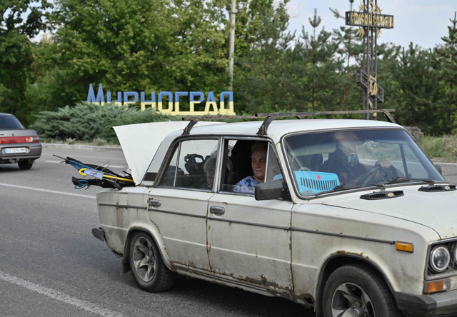 People ride in a car loaded with belongings as they leave the town of Myrnohrad on August 26, 2024 (AFP photo)