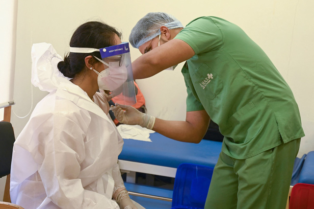 A medical worker inoculates a woman wearing a personal protective quiopment suit with a dose of the Covishield COVID-19 coronavirus vaccine at Max hospital in New Delhi on Monday (AFP photo)