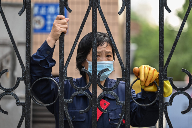 A worker looks past a fence in a compound during a COVID-19 coronavirus lockdown in the Jing'an district of Shanghai on Wednesday (AFP photo)
