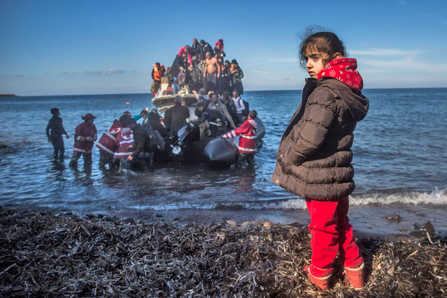 A Syrian girl stands on the shore as refugees from Syria and Iraq disembark on the Greek island of Lesbos after arriving with other 120 people on a wooden boat from the Turkish coast on Monday (AP photo)