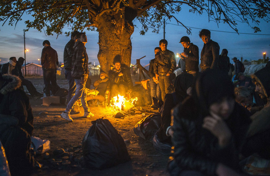 Migrants and refugees keep warm around a bonfire as they wait to enter a registration camp after crossing the border between Greece and the former Yugoslav Republic of Macedonia near Gevgelija on Sunday  (AFP photo)