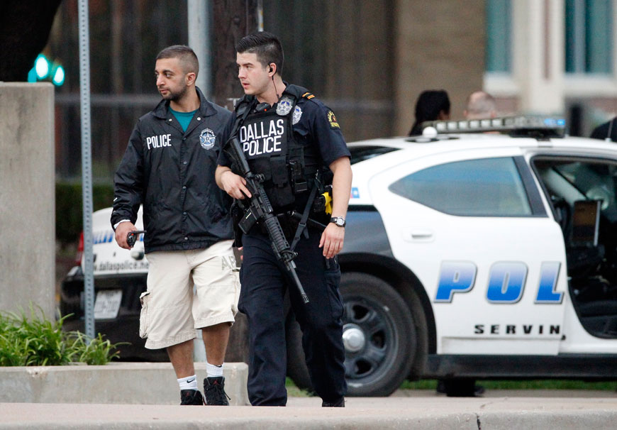 Dallas police officers walk down Belleview Street, one block away from police headquarters, searching the area on Saturday (AP photo)