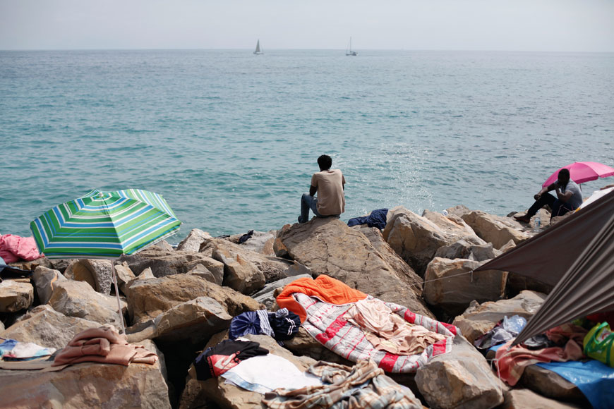 Migrants sit on the rocky beach at the Franco-Italian border in Ventimiglia, Italy, during the holy month of Ramadan, on Friday (AP photo)
