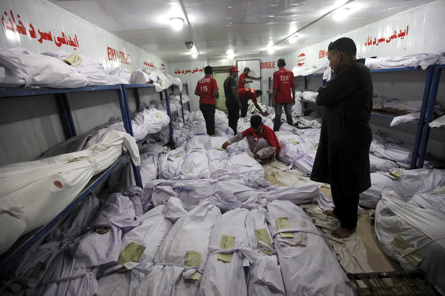 A relative (right) waits while volunteers search for a body of a deceased among people who died due to an intense heatwave, at Edhi Foundation morgue in Karachi, Pakistan, on Monday (Reuters photo)