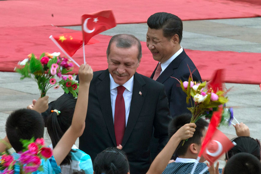 Turkey’s President Recep Tayyip Erdogan (centre) and Chinese President Xi Jinping (right) are greeted by Chinese children jumping and waving Turkish and Chinese national flags during a welcome ceremony at the Great Hall of the People in Beijing on Wednesday (AP photo)