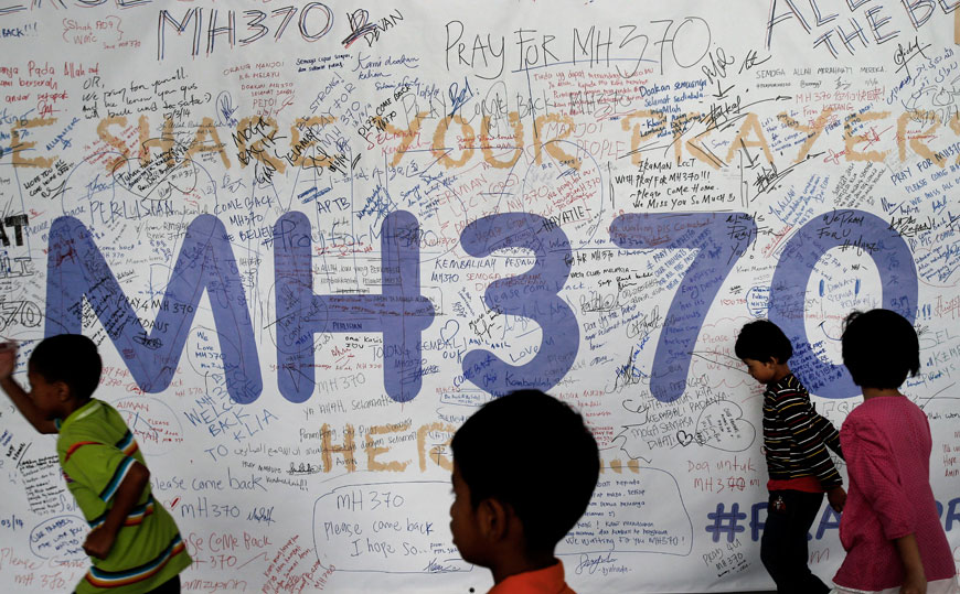 In this March 13, 2014, photo, children run past dedication messages left for passengers and others involved with the missing Malaysia Airlines jetliner MH370 on the walls of the Kuala Lumpur International Airport in Sepang, Malaysia (AP photo)