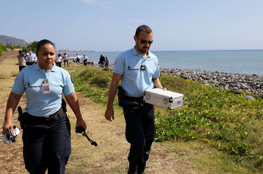 Police officers leave the scene with container holding metallic debris found on a beach in Saint-Denis on the French Reunion Island in the Indian Ocean on Sunday, close to where a Boeing 777 wing part believed to belong to missing Flight MH370 washed up last week (AFP photo)