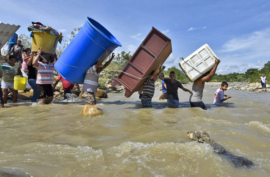 Colombians deported from Venezuela return for their belongings and carry them across the Tachira River, on the border between the two countries, to Cucuta, in the Colombian North of Santander Department, on Tuesday (AFP photo)