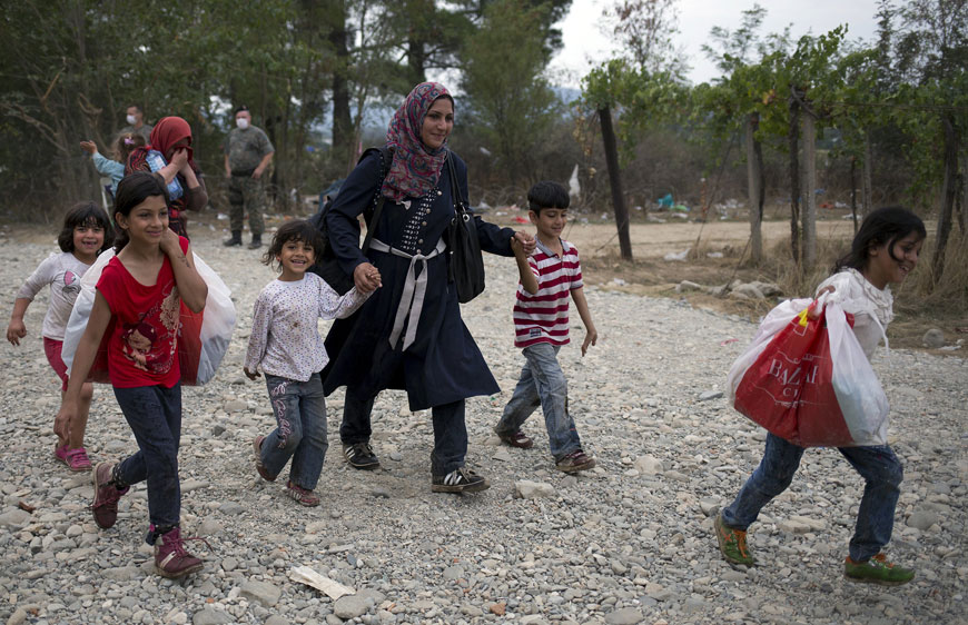 A migrant woman walks with children on a dirty road after crossing the border between former Yugoslav Republic of Macedonia and Greece near Gevgelija, on Sunday (Reuters photo)