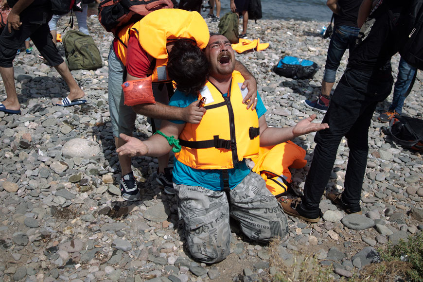 Syrian refugees react as they arrive after crossing aboard a dinghy from Turkey, on the island of Lesbos, Greece, on Monday (AP photo)