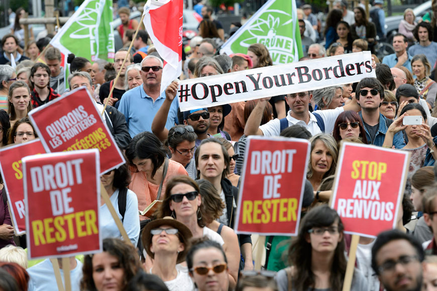 People take part in a demonstration in support of migrants holding up various placards with slogans welcoming refugees at the place Neuve, Switzerland, on Saturday (AP photo)