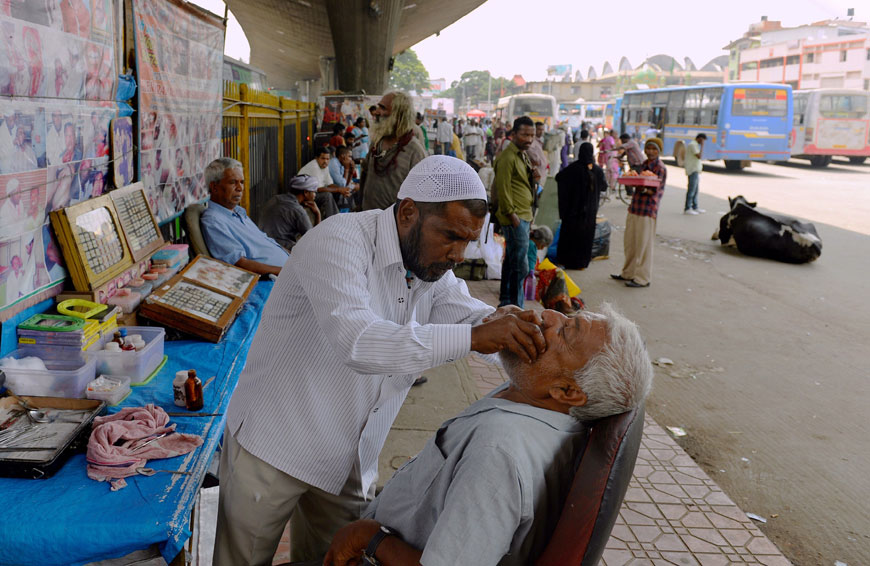 In this photograph taken on May 5, traditional Indian dental worker Allah Baksh takes measurements for dentures from a customer at his roadside stall at KR Market bus stand in Bangalore (AFP photo)