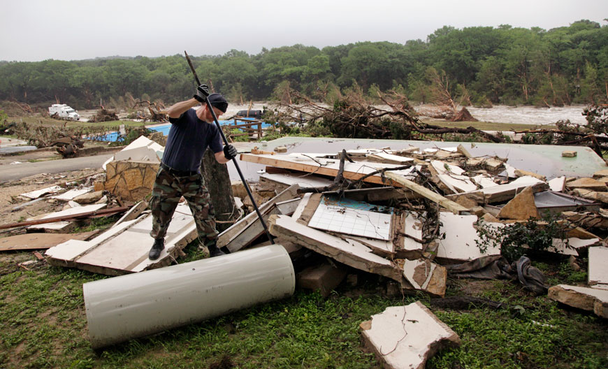 Kevin Calaway pries apart debris from a cabin shattered from a flood days earlier at a resort along the Blanco River, Tuesday (AP photo)