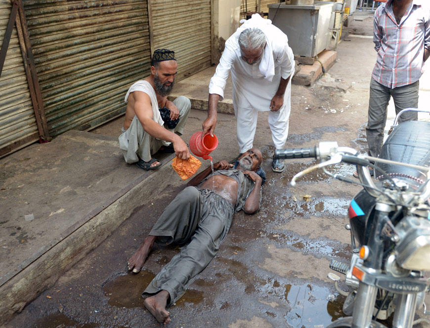 A Pakistani resident helps a heatstroke victim at a market area during a heatwave in Karachi on Tuesday (AFP photo)