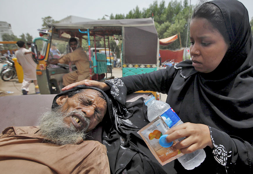 A woman wets her burka to cool her father’s head outside the Jinnah Postgraduate Medical Centre in Karachi on Wednesday (Reuters photo)