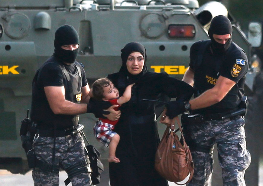 Two Hungarian riot policemen escort a migrant woman and her child in Roszke, Hungary, on Wednesday (Reuters photo)