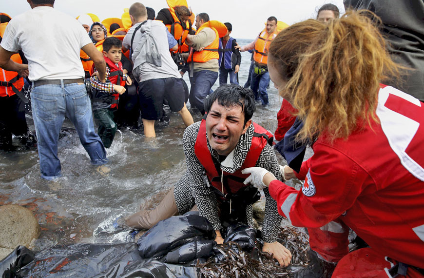 A Greek Red Cross volunteer comforts a crying Syrian refugee moments after disembarking from a flooded raft at a beach on the Greek island of Lesbos after crossing a part of the Aegean Sea from the Turkish coast on an overcrowded raft on Tuesday (Reuters photo)