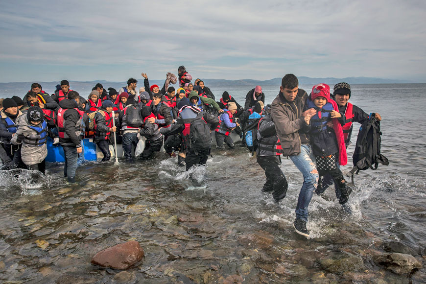 Migrants and refugees disembark safely from a dinghy at a beach on the Greek island of Lesbos after crossing the Aegean Sea from the Turkish coast, on Monday (AP photo)