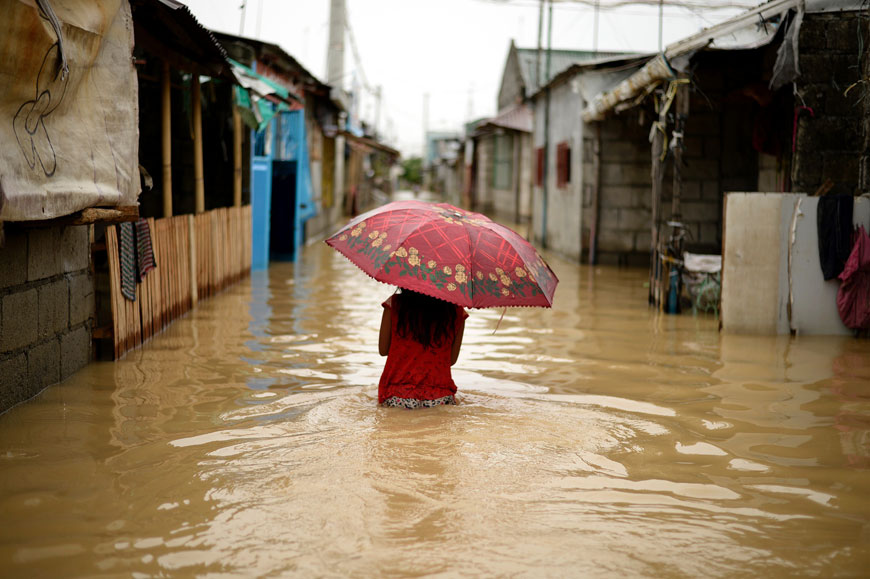 A girl with an umbrella wades through a flooded street in Calumput, Bulacan, suburban Manila, on Sunday (AFP photo)