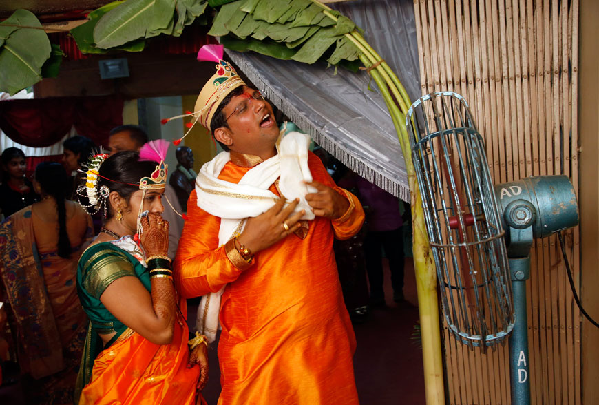 A newly wed couple Nilesh (right) and Meenal Bhagat stand in front of a fan to cool themselves after an hour-long ritual on a hot summer day in Mumbai on Saturday (AP photo)