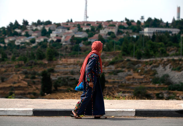 A Palestinian woman walking in Al Bireh, north of the city of Ramallah in the Israeli-occupied West Bank, stares at the Israeli settlement of Basgot, on Monday (AFP photo)