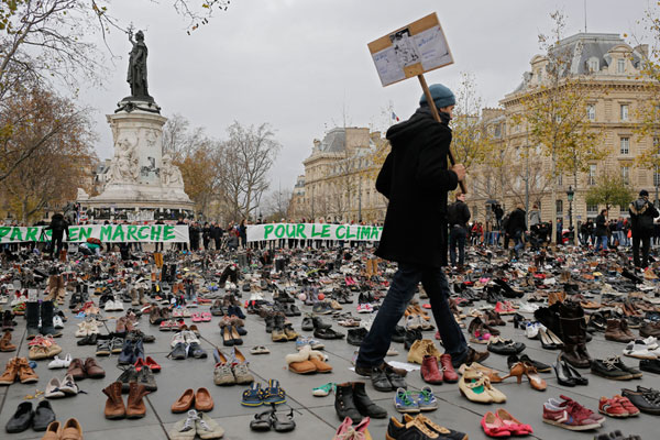 A man walks between shoes as hundreds of pairs of shoes are displayed at the Place de la Republique, in Paris, as part of a symbolic and peaceful rally called by the NGO Avaaz ‘Paris sets off for climate’, on Sunday (AP photo)