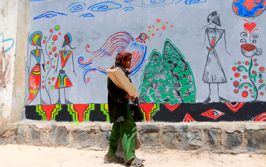 A Yemeni youth walks past a wall bearing a graffiti, to mark the National Day of Yemeni coffee, in the capital Sanaa, on Tuesday (AFP photo)