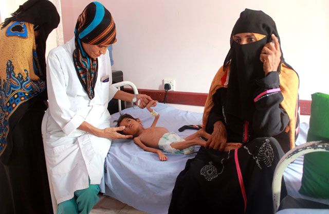 A medical care worker examines a Yemeni child suffering from malnutrition, as women look on, at a treatment centre in Yemen's northern Hajjah province on Sunday (AFP photo)
